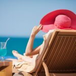 woman on sun lounger in sun with cocktail from behind