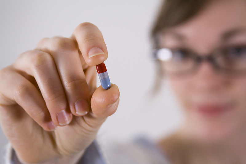 Person with glasses holding pill