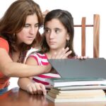 worried mum checks teens internet browsing on laptop