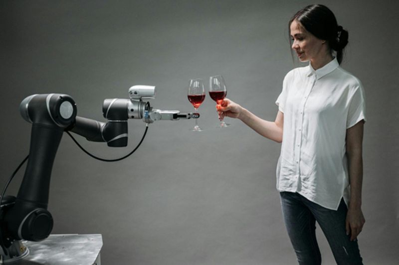 woman toasts with glass of wine with robot arm