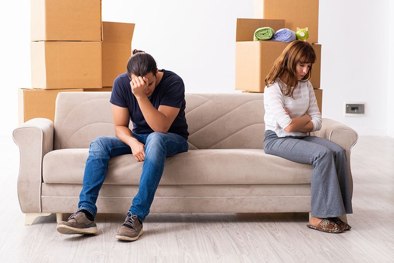 young couple on sofa moving unhappy